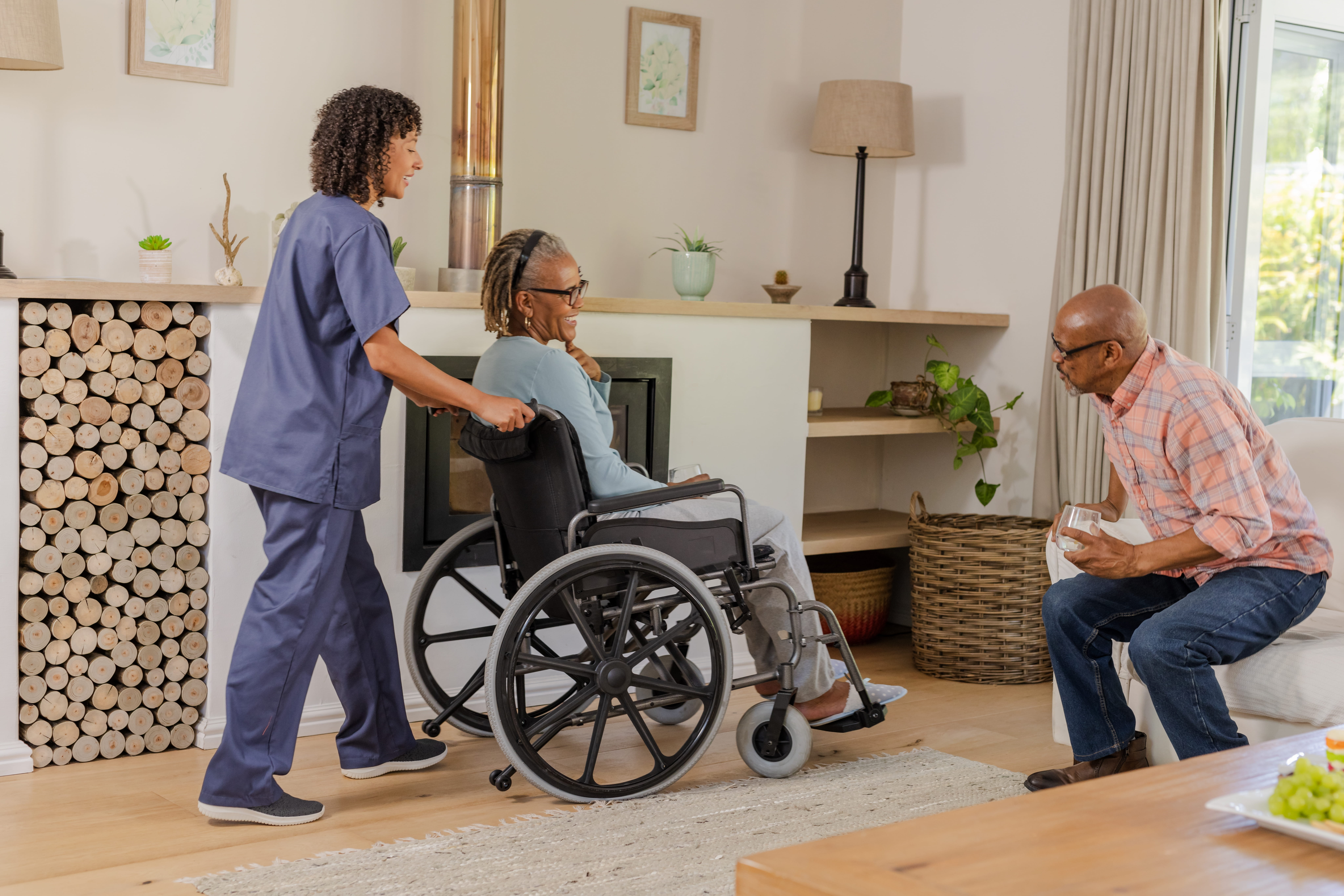 Caregiver assisting a resident in a wheelchair in a comfortable home living room