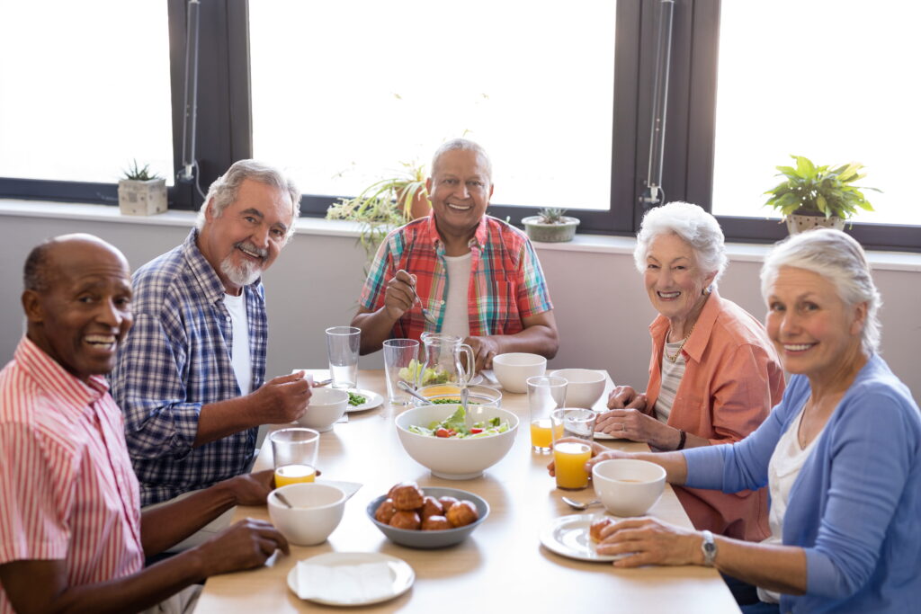 Residents sharing a home-cooked meal together at a bright dining table by the windows
